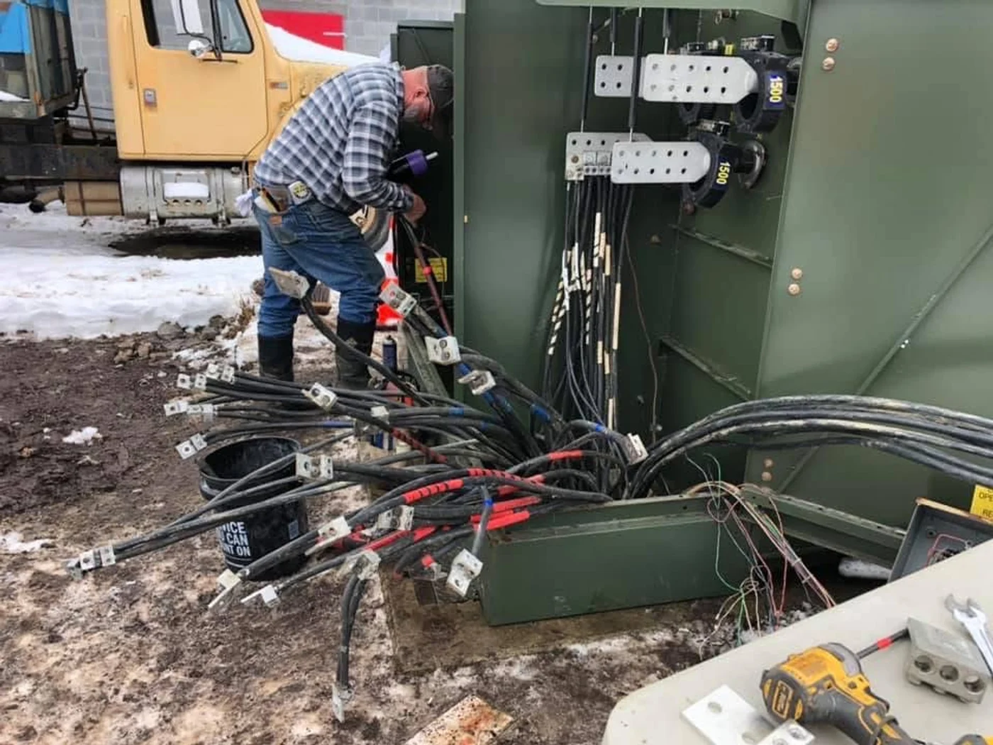 Electrician terminating high-voltage cables at commercial switchgear