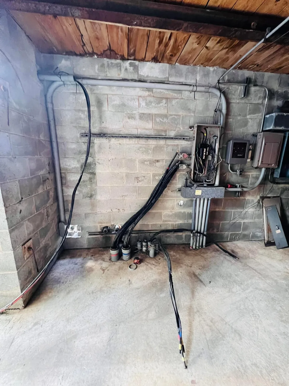 Electrical panel wiring in progress on concrete block wall