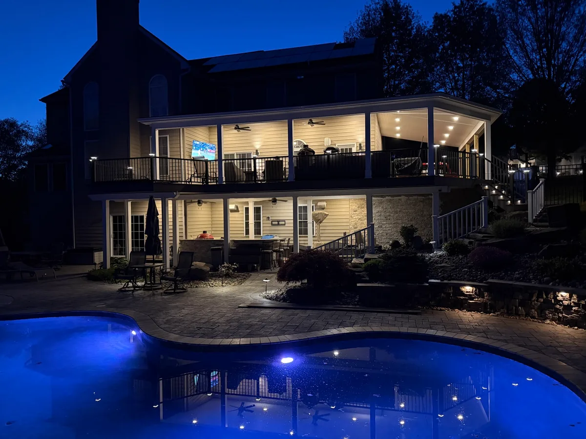 Full outdoor entertainment area at night — pool lighting, deck recessed lighting, and landscape fixtures