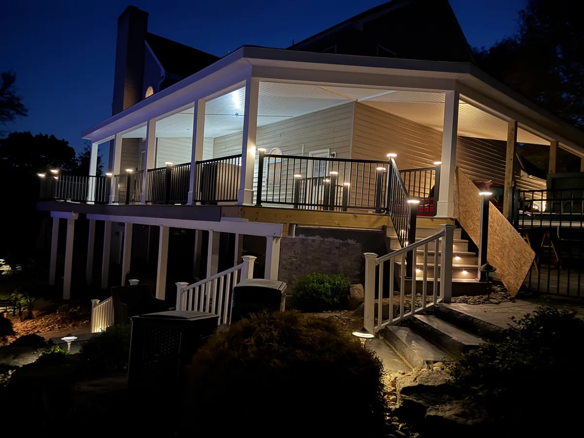 Two-story deck with under-rail lighting, stair lighting, and landscape uplighting at dusk